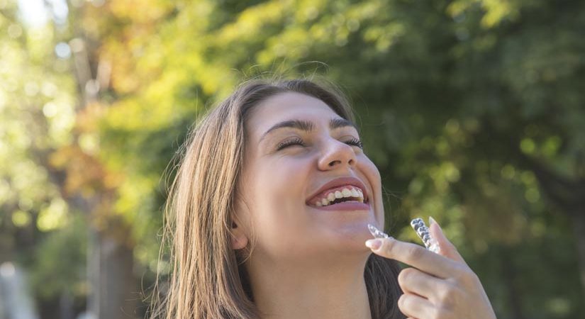 Beautiful smiling Turkish woman is holding an invisalign bracer