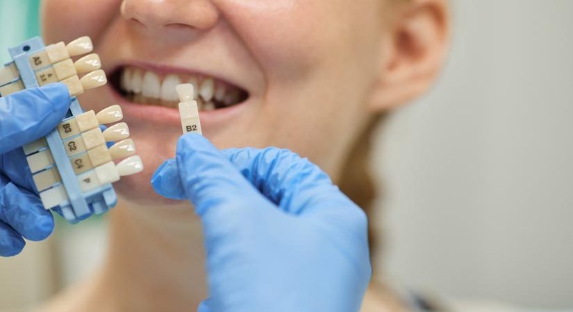 Close-up of patient showing her teeth while dentist choosing implants for her